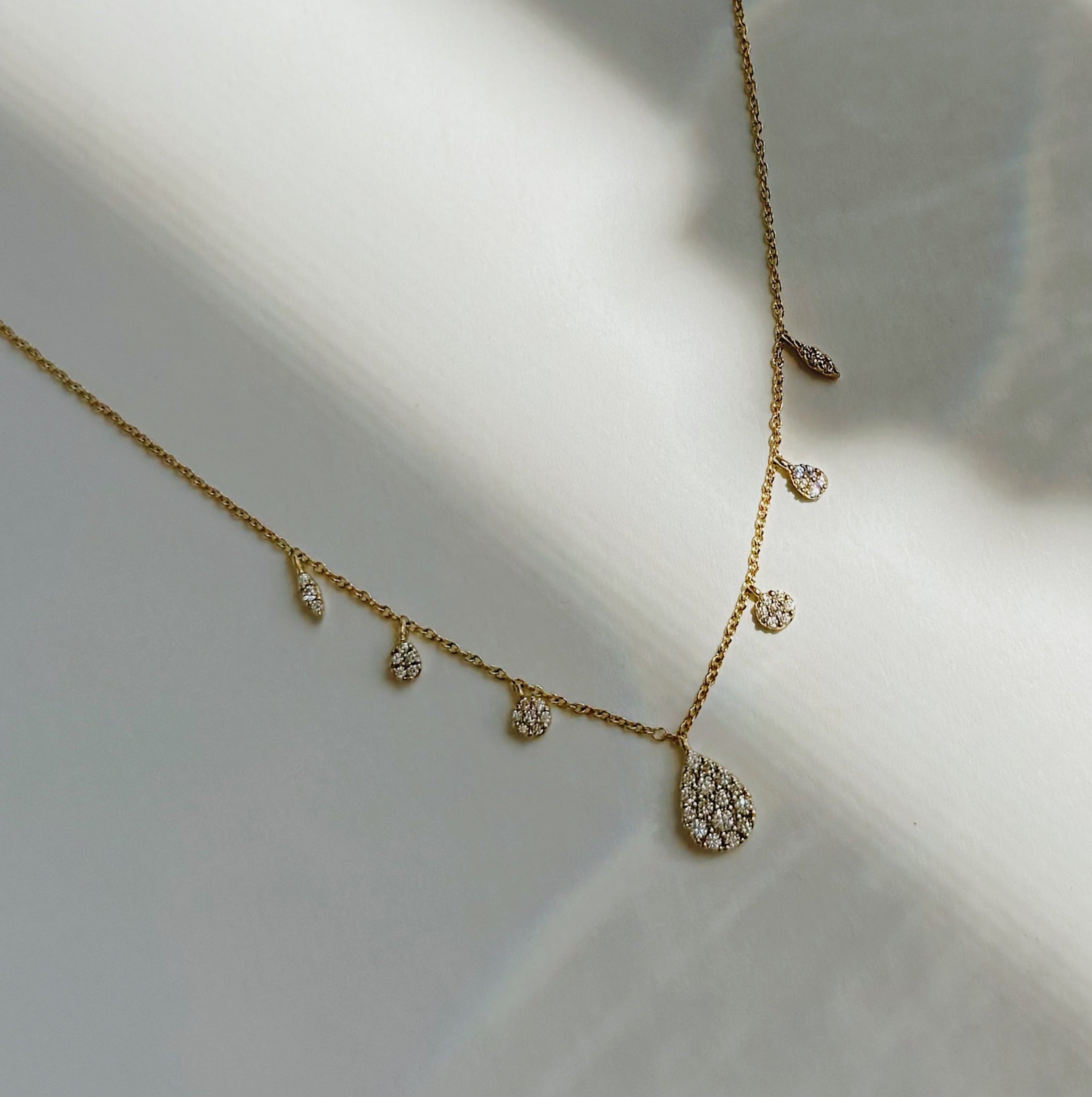 Delicate gold necklace with small pendants on a light background