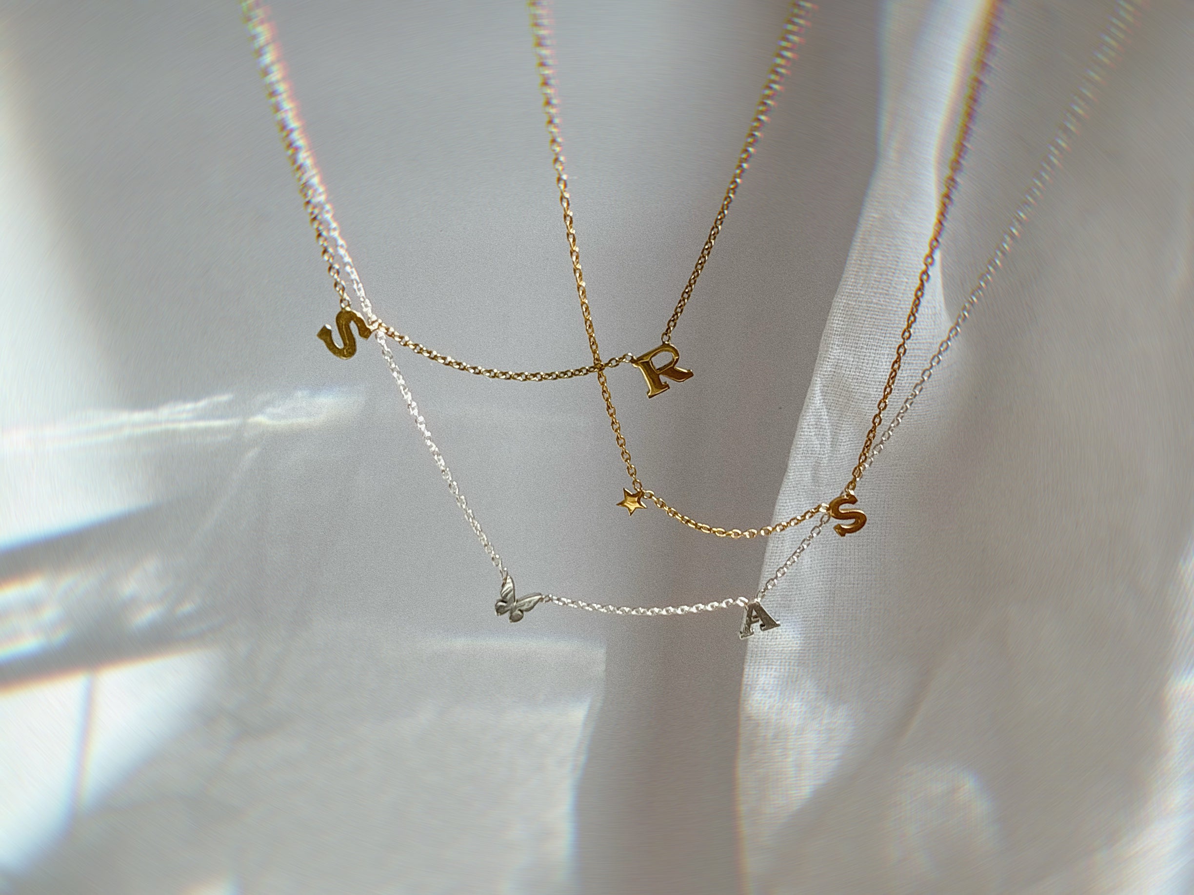 Gold necklaces with letter pendants on a white background