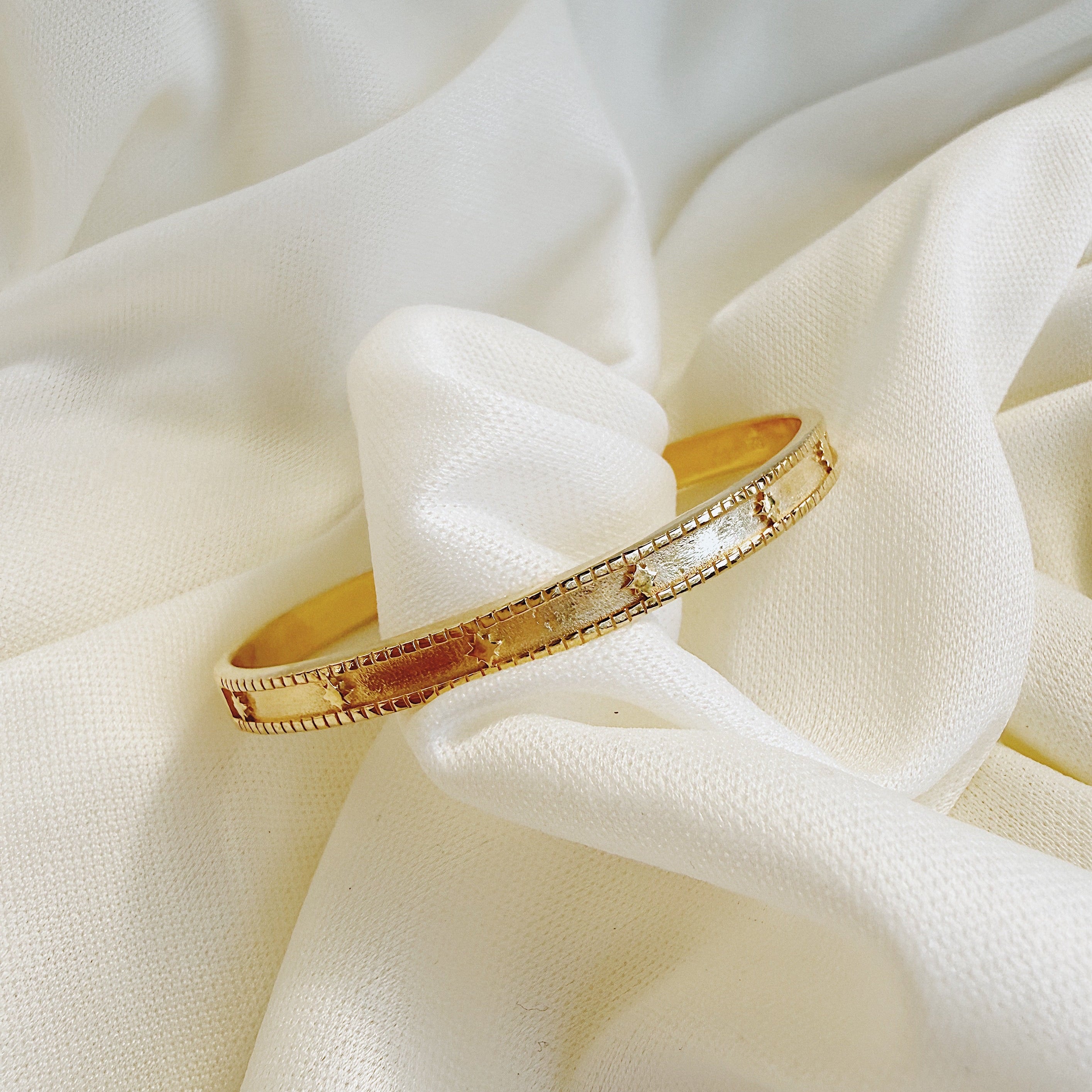 Gold bracelet on a soft white fabric background